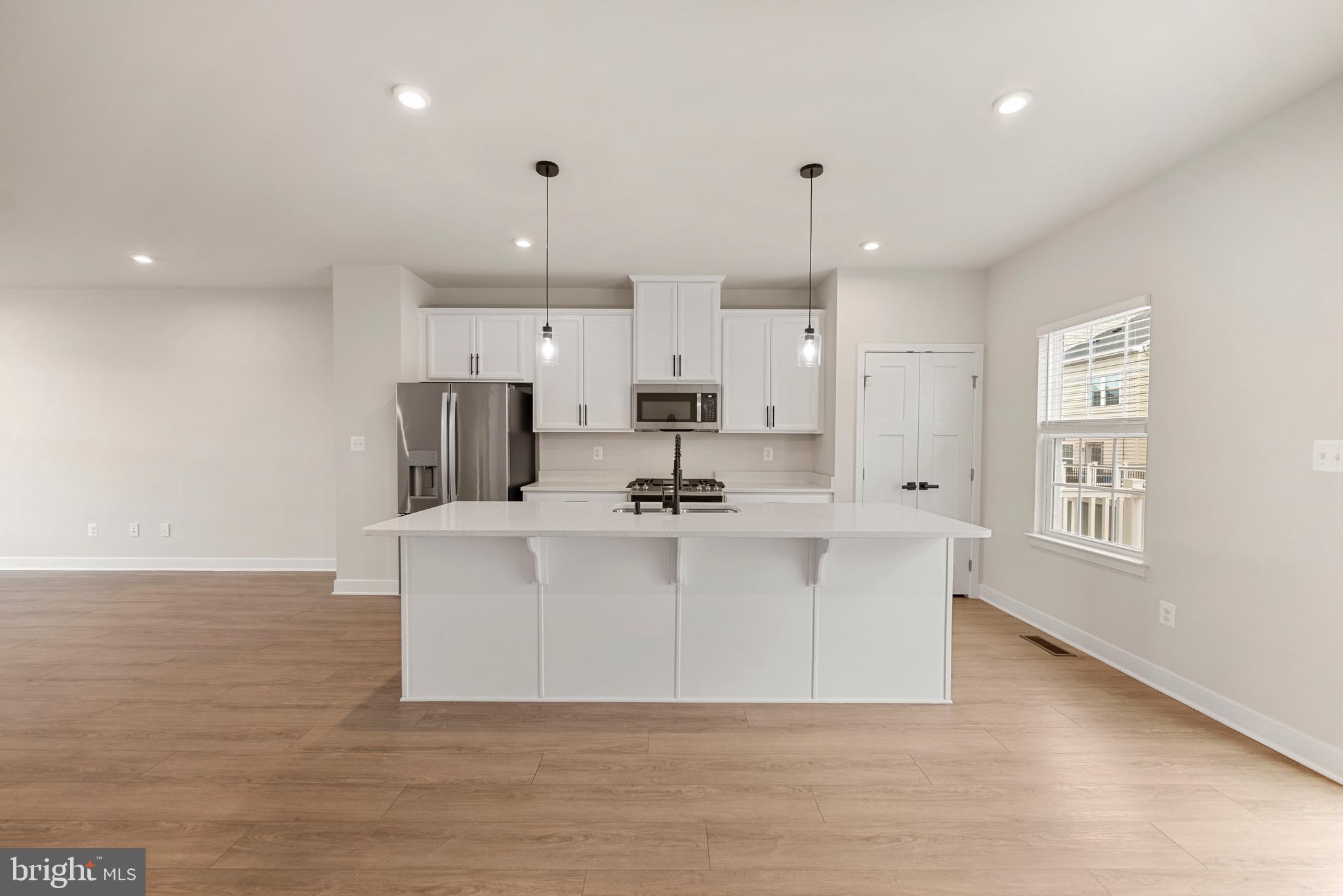 a view of kitchen with stainless steel appliances granite countertop a sink a stove a refrigerator and white cabinets