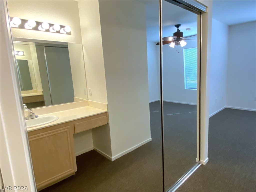 8070 West Russell Road, Unit 2105 Las Vegas, NV 89113 - Photo 6 of 10 A well-lit vanity with a mirrored closet door reflects a spacious bedroom with carpeted flooring.