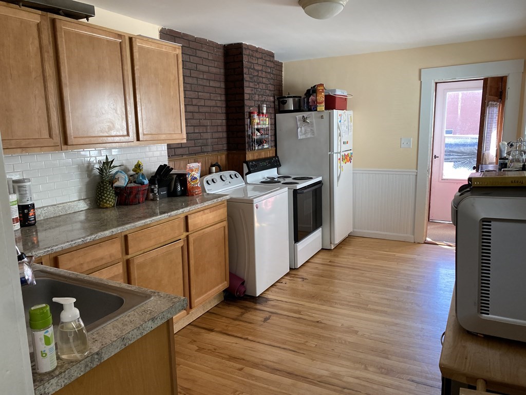 285 High Street Lowell, MA 01852 - Photo 6 of 8 a kitchen with stainless steel appliances granite countertop a sink dishwasher stove and refrigerator with wooden floor