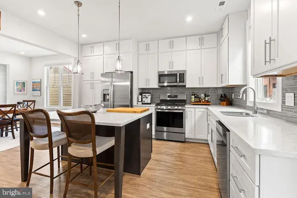 a dining room with stainless steel appliances kitchen island granite countertop a dining table and chairs with wooden floor