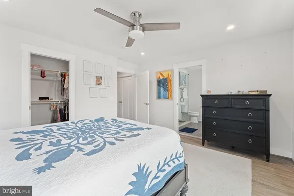 a spacious bedroom with a bed painting on wall and windows