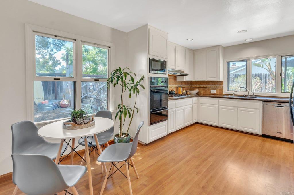 1528 Juniperhill Drive Encinitas, CA 92024 - Photo 13 of 40 a kitchen with stainless steel appliances granite countertop a stove top oven a sink a dining table and chairs with wooden floor