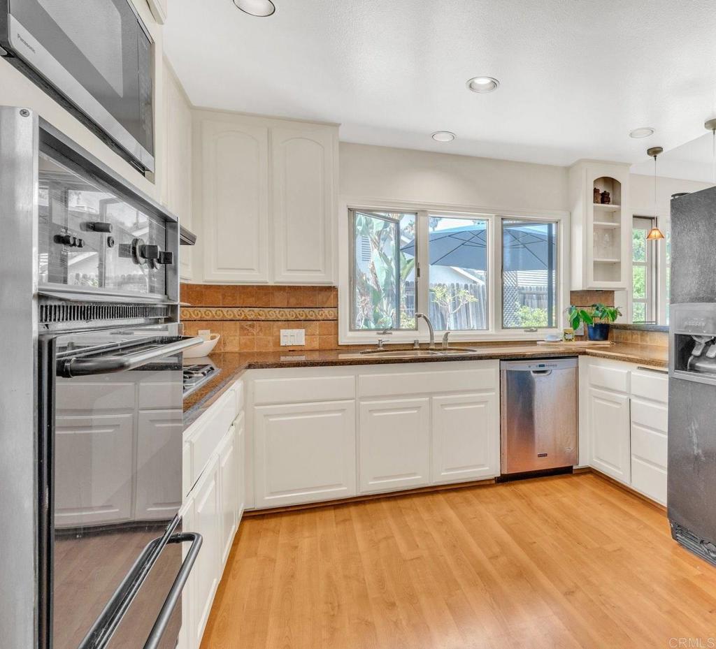 1528 Juniperhill Drive Encinitas, CA 92024 - Photo 14 of 40 a large white kitchen with a sink and dishwasher a stove top oven with wooden floor