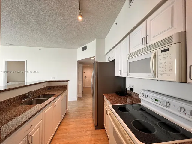 a kitchen with stainless steel appliances kitchen island a stove a refrigerator and a sink