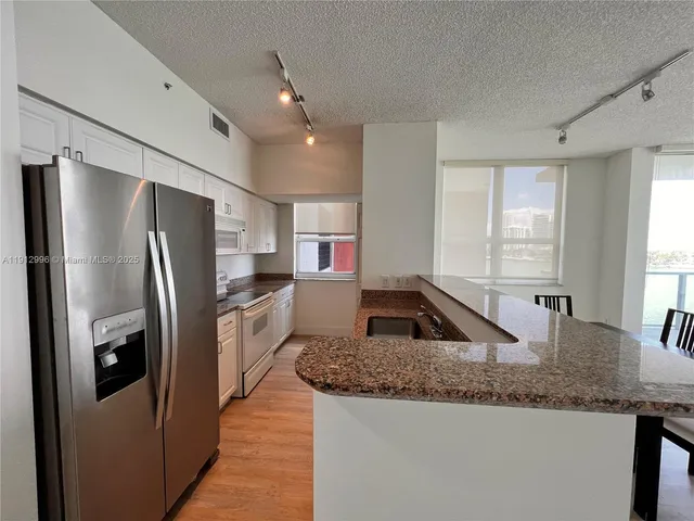 a kitchen with stainless steel appliances granite countertop a sink a refrigerator and a granite counter tops