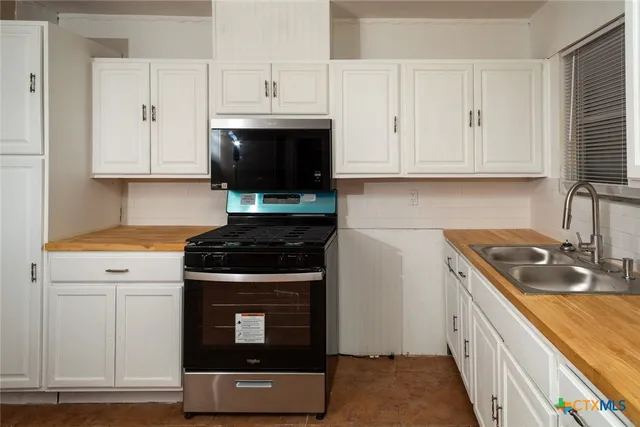 a kitchen with stainless steel appliances white cabinets and a stove a sink