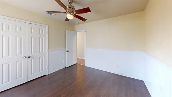 an empty room with wooden floor and a ceiling fan