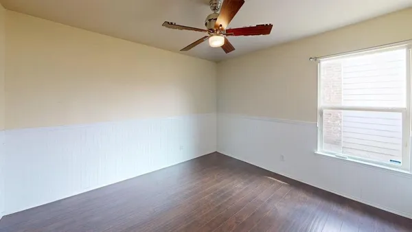 a view of an empty room with a window and wooden floor
