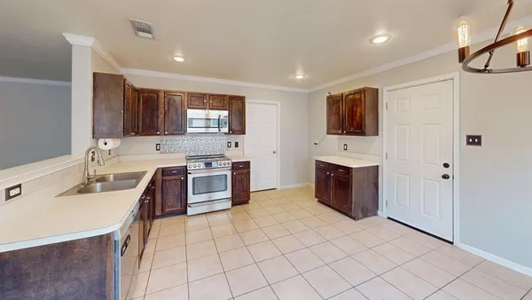 a large kitchen with stainless steel appliances a stove top oven a sink a microwave and a refrigerator