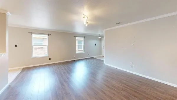an empty room with wooden floor and windows