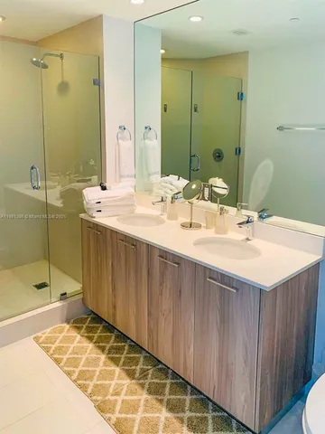 a bathroom with a double vanity sink mirror and shower