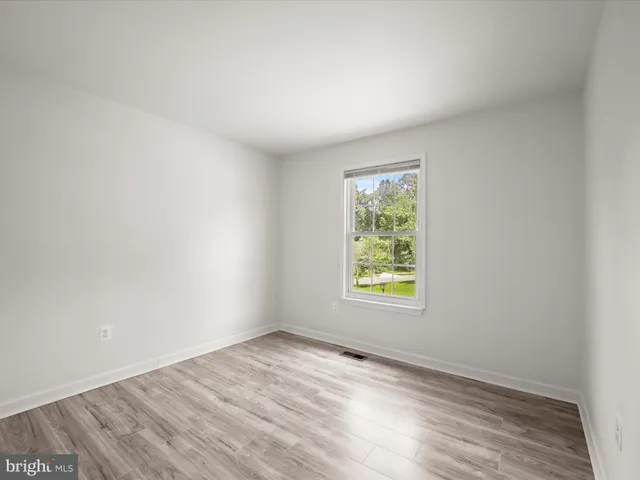 an empty room with wooden floor and window