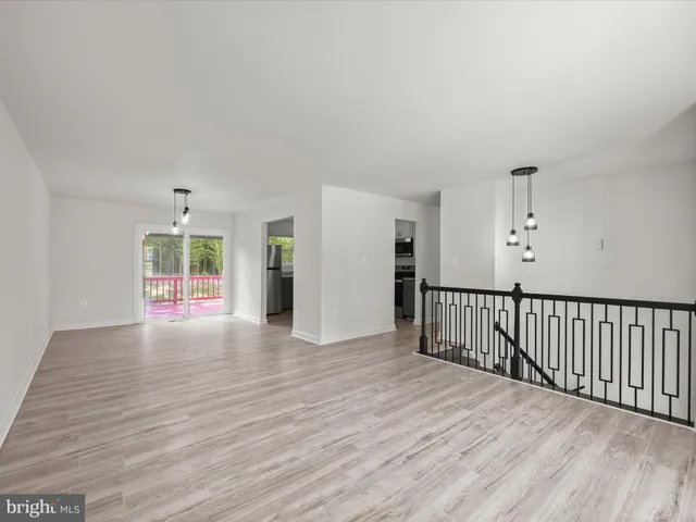 a view of an empty room with wooden floor and windows