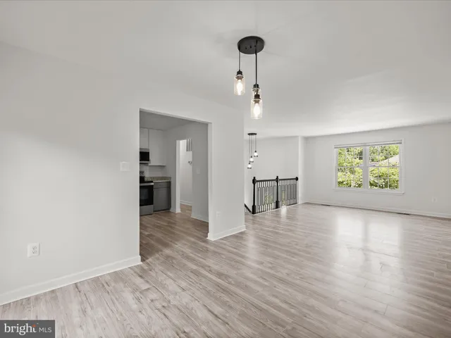 a view of an empty room with window and wooden floor