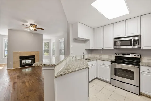 a kitchen with granite countertop a stove top oven a sink and a microwave