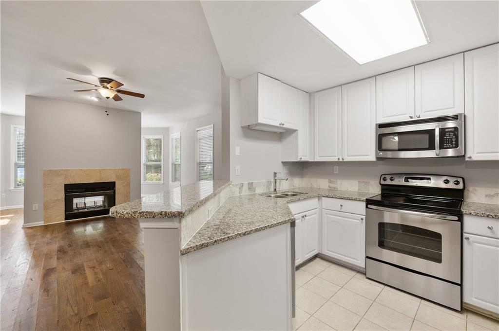 a kitchen with granite countertop a stove top oven a sink and a microwave