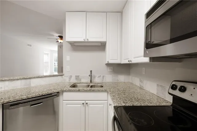 a kitchen with stainless steel appliances granite countertop a sink stove and cabinets