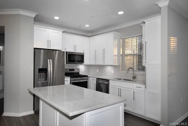 a kitchen with a sink a stove a refrigerator a center island and a window