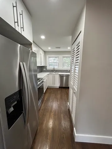 a kitchen with stainless steel appliances granite countertop a refrigerator a sink dishwasher a stove and white countertops with wooden floor