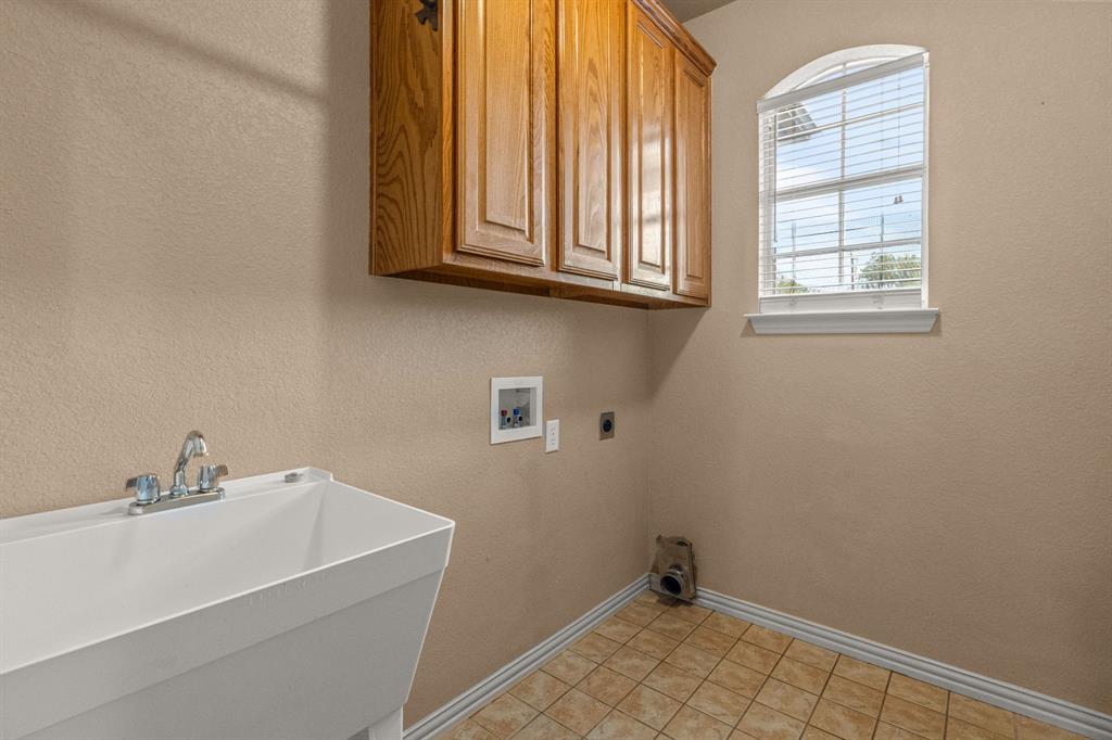 6501 Indian Trail Sanger, TX 76266 - Photo 20 of 40 Laundry area featuring a textured wall, hookup for a washing machine, hookup for an electric dryer, cabinet space, and light tile patterned floors