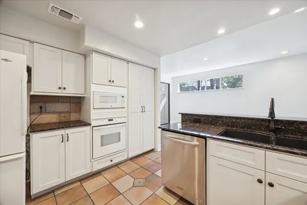 a spacious bathroom with a granite countertop sink a toilet a mirror and shower
