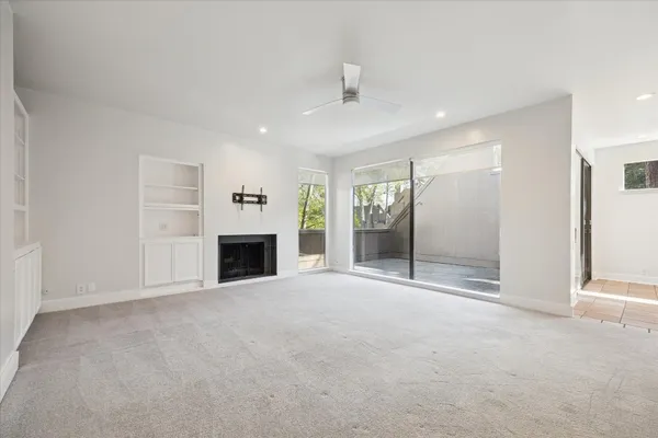 an empty room with windows and fireplace