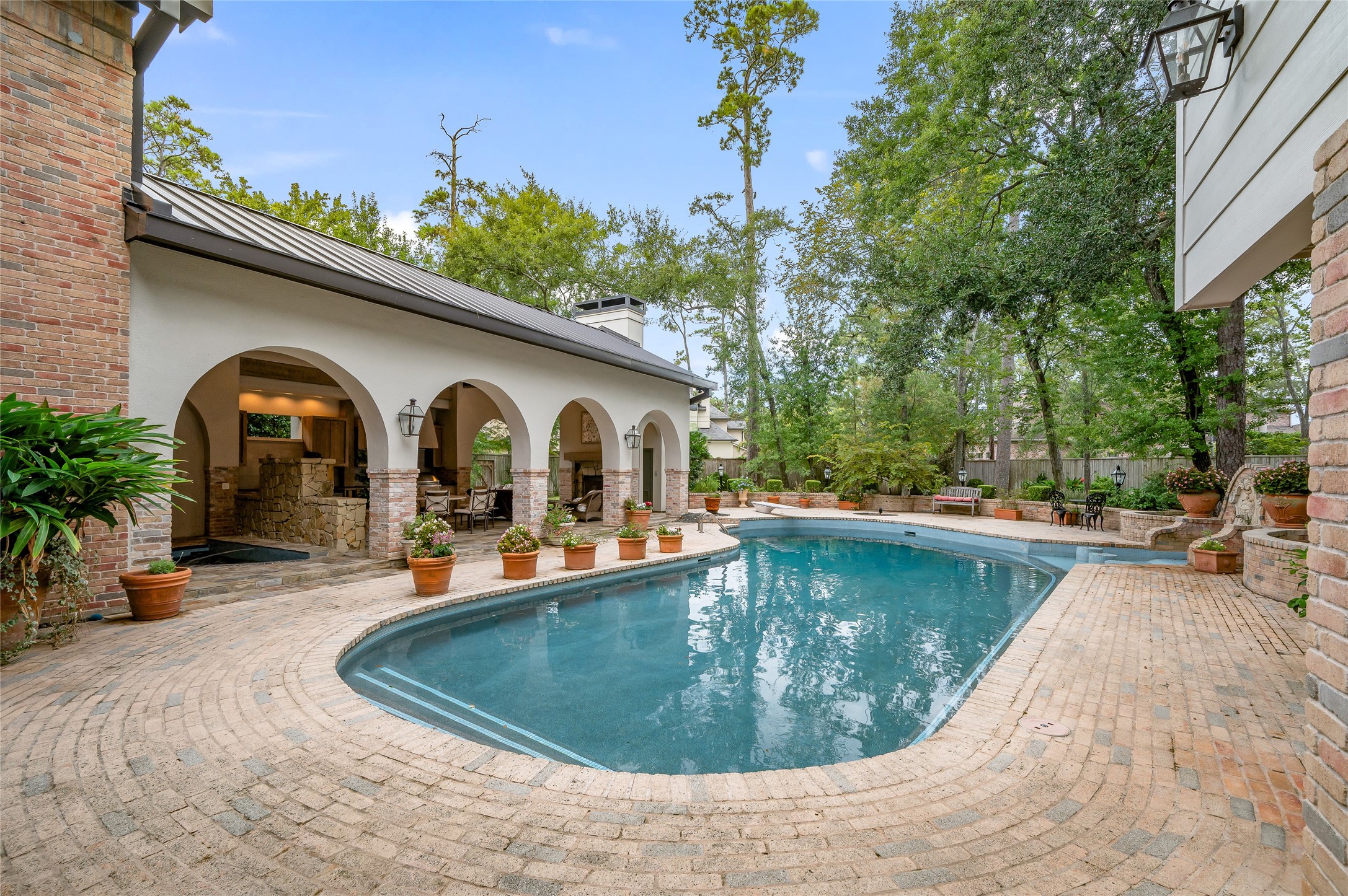 11518 Shadow Way Street Houston, TX 77024 - Photo 45 of 50 This view highlights the generous pool with a diving board, tile-inlaid seating stools, and expansive deck, ideal for summer entertaining.