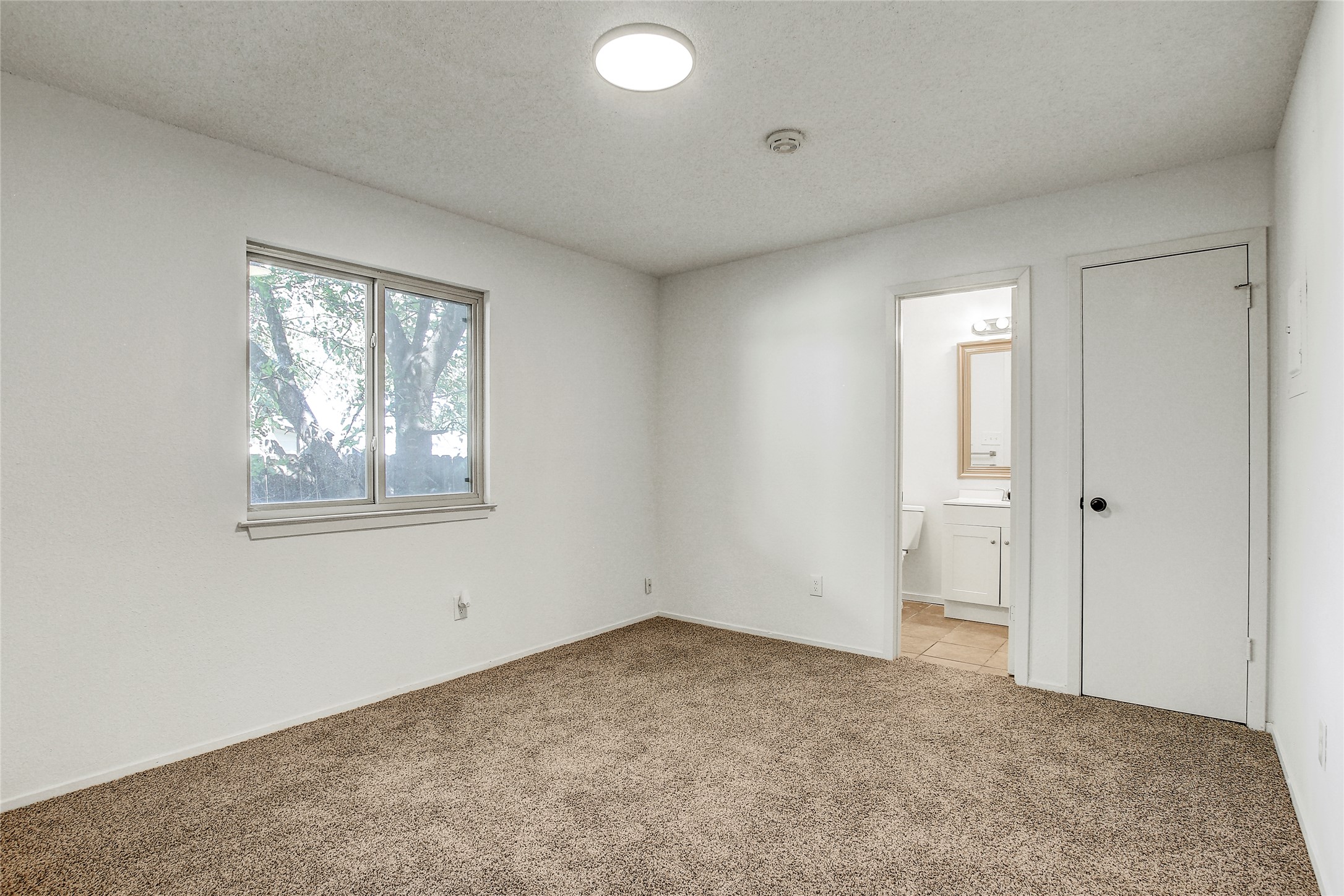 902 King Albert Street, Unit B Austin, TX 78745 - Photo 12 of 16 Unfurnished bedroom featuring light colored carpet, a textured ceiling, and ensuite bath