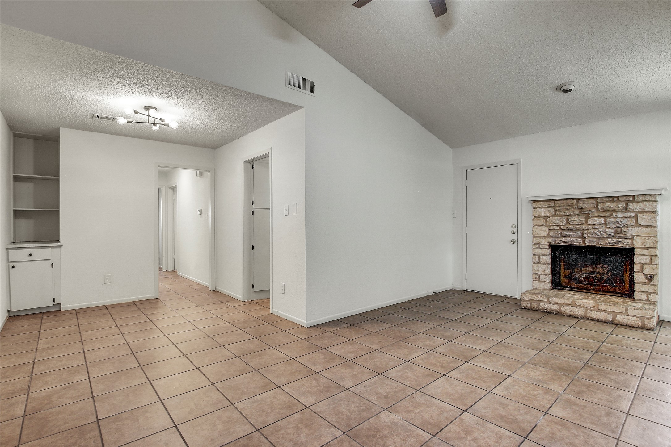 902 King Albert Street, Unit B Austin, TX 78745 - Photo 4 of 16 Unfurnished living room featuring a high textured ceiling, a fireplace, and light tile patterned floors