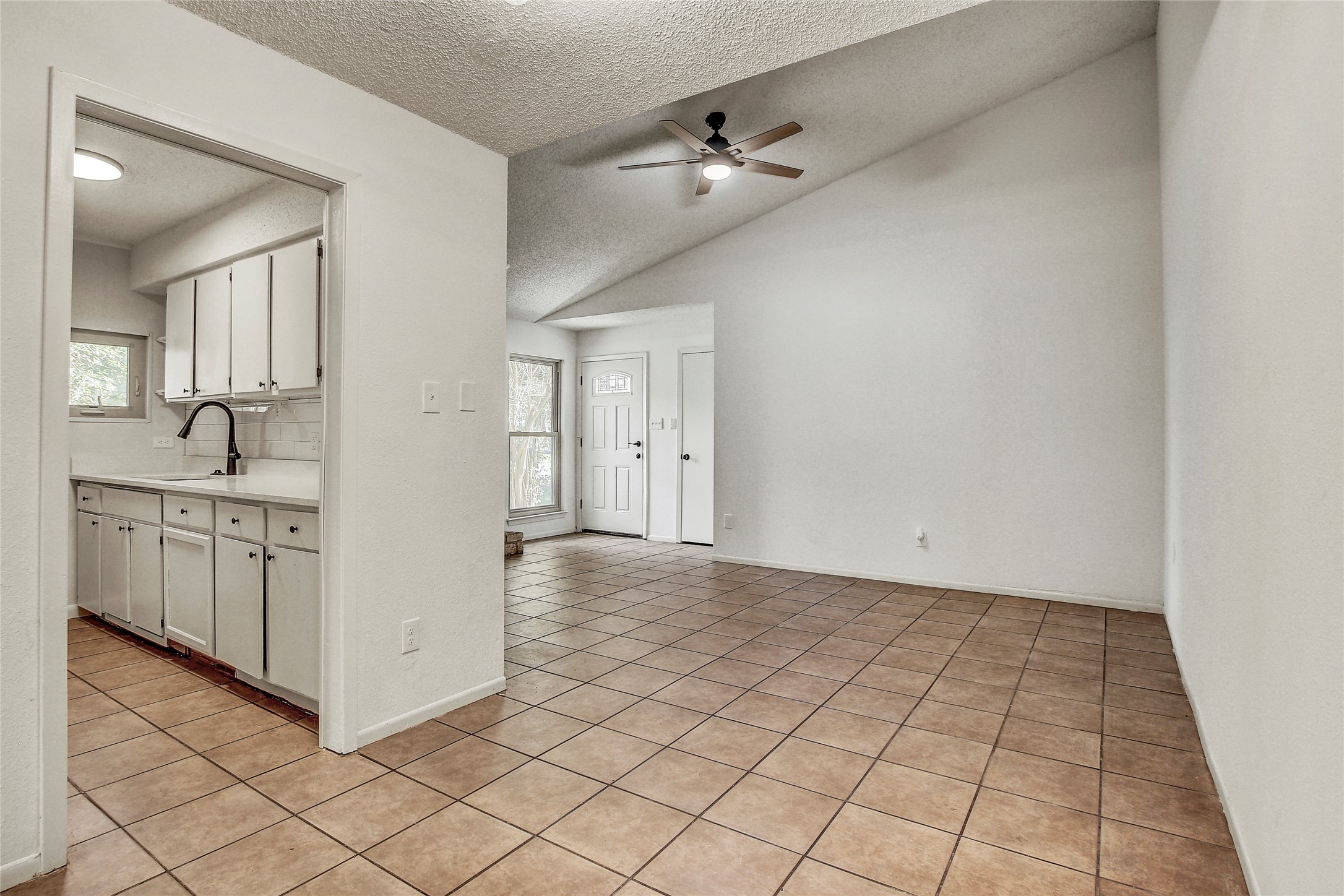 902 King Albert Street, Unit B Austin, TX 78745 - Photo 6 of 16 Kitchen with light countertops, light tile patterned flooring, white cabinetry, ceiling fan, and healthy amount of natural light