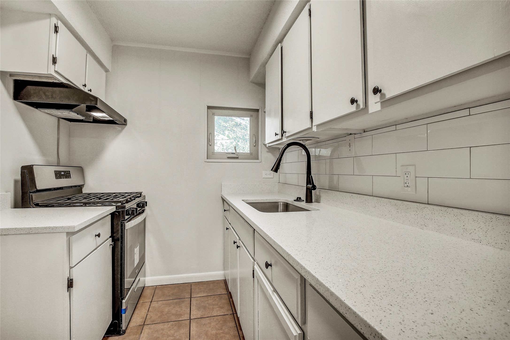 902 King Albert Street, Unit B Austin, TX 78745 - Photo 7 of 16 Kitchen with stainless steel gas range, white cabinetry, crown molding, light stone countertops, and backsplash