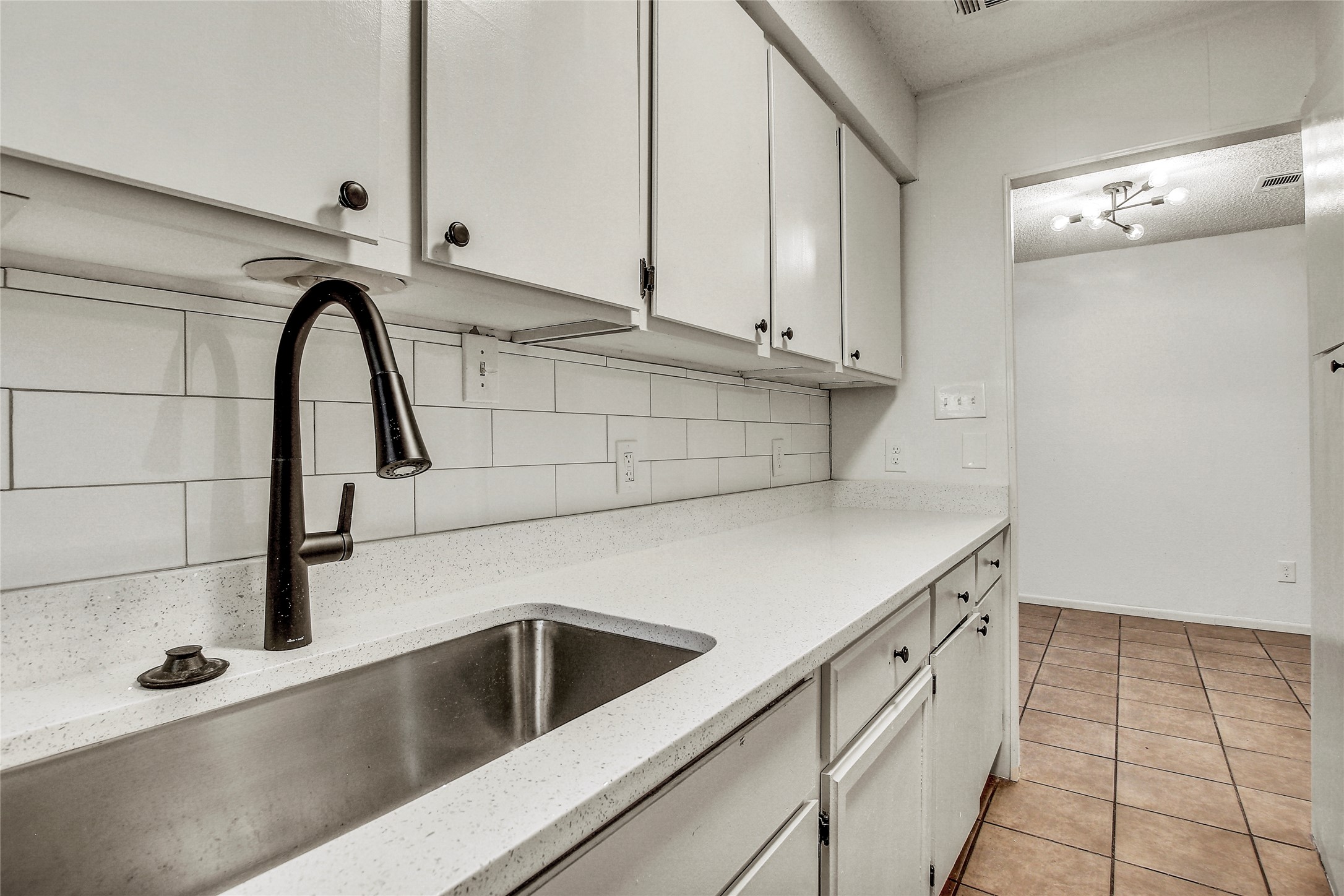 902 King Albert Street, Unit B Austin, TX 78745 - Photo 8 of 16 Kitchen with white cabinets, light tile patterned flooring, tasteful backsplash, and light stone counters