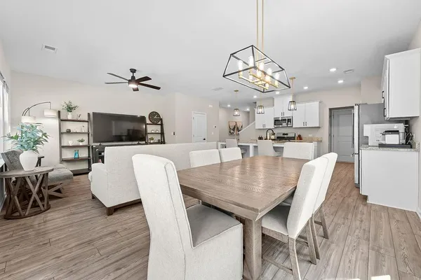 a dining room with wooden floor a chandelier a wooden table and chairs