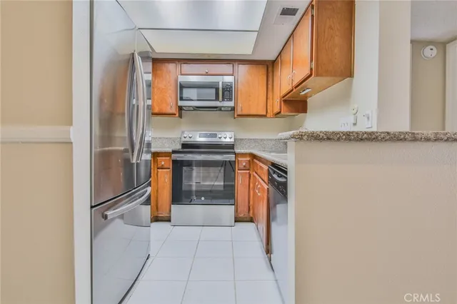 a kitchen with stainless steel appliances granite countertop a refrigerator and a stove top oven