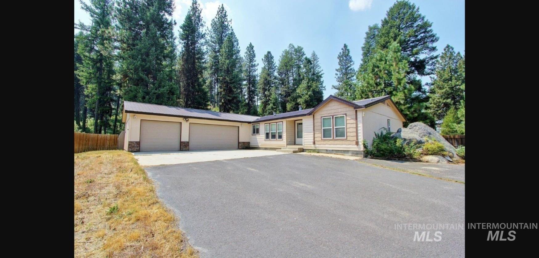 Ranch-style residence featuring a three-car garage and a large asphalt driveway