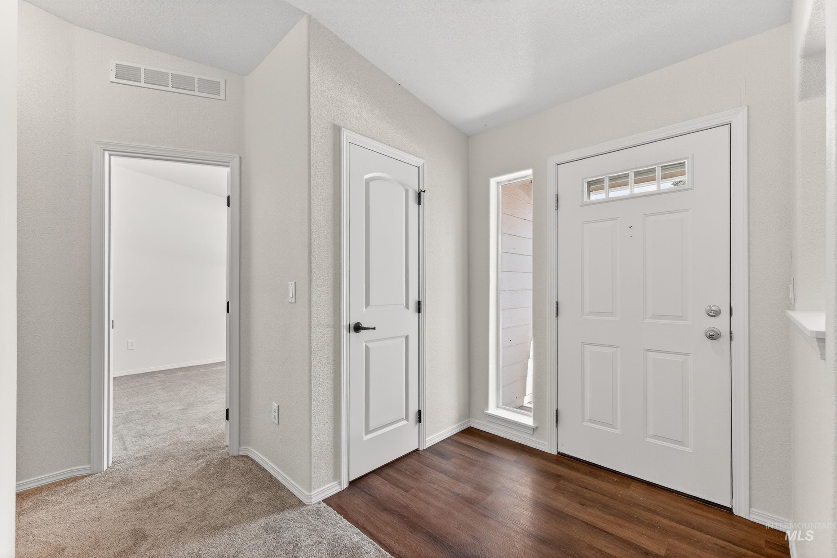 1649 Crown Point Parkway Cascade, ID 83611 - Photo 2 of 24 Entryway featuring a paneled front door with an integrated transom window, wood-finish flooring, a sidelight window, and a paneled interior door with matte black hardware