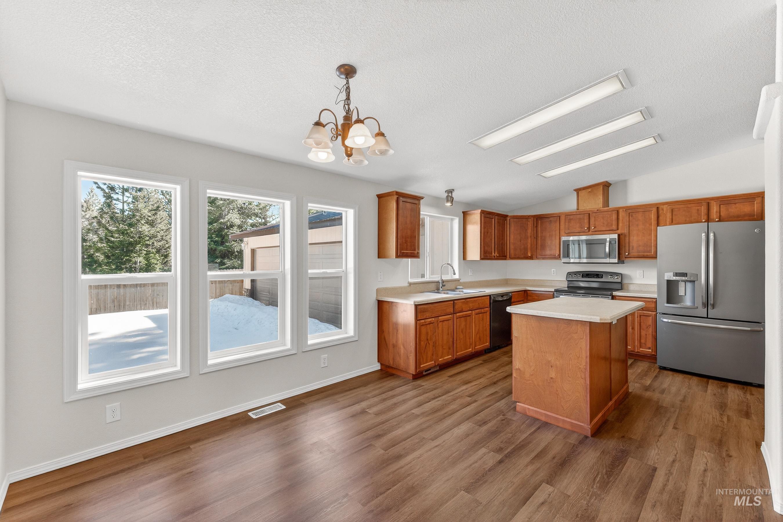1649 Crown Point Parkway Cascade, ID 83611 - Photo 3 of 24 Open-concept kitchen and dining area featuring wood-finish flooring, a central island with a solid surface countertop, wood cabinetry, and stainless steel appliances