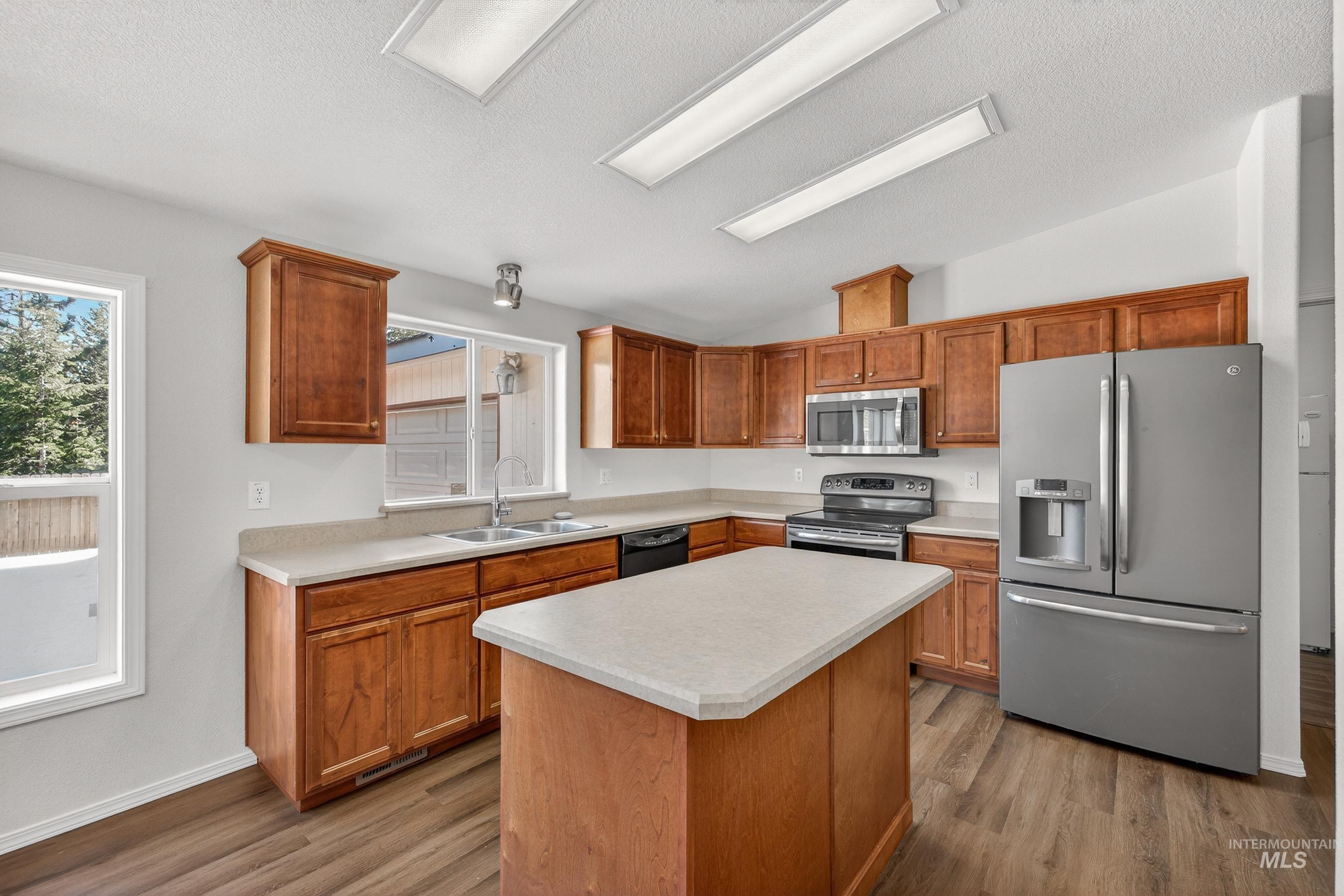1649 Crown Point Parkway Cascade, ID 83611 - Photo 7 of 24 Kitchen featuring wood cabinetry, light-toned countertops, a stainless steel refrigerator, stainless steel microwave, and wood-finish flooring