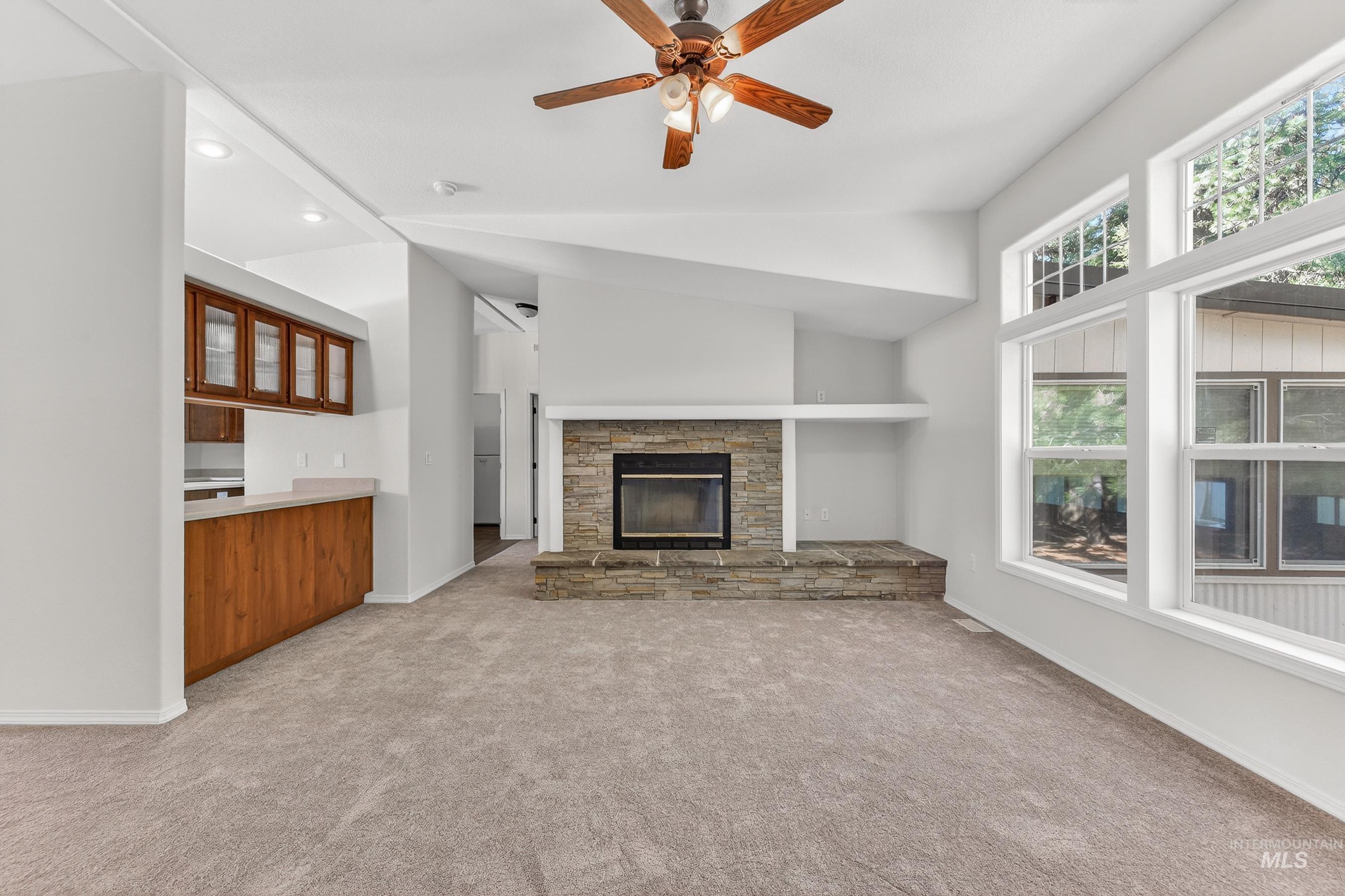 1649 Crown Point Parkway Cascade, ID 83611 - Photo 8 of 24 Living area featuring a stone fireplace with hearth, vaulted ceilings, and large windows