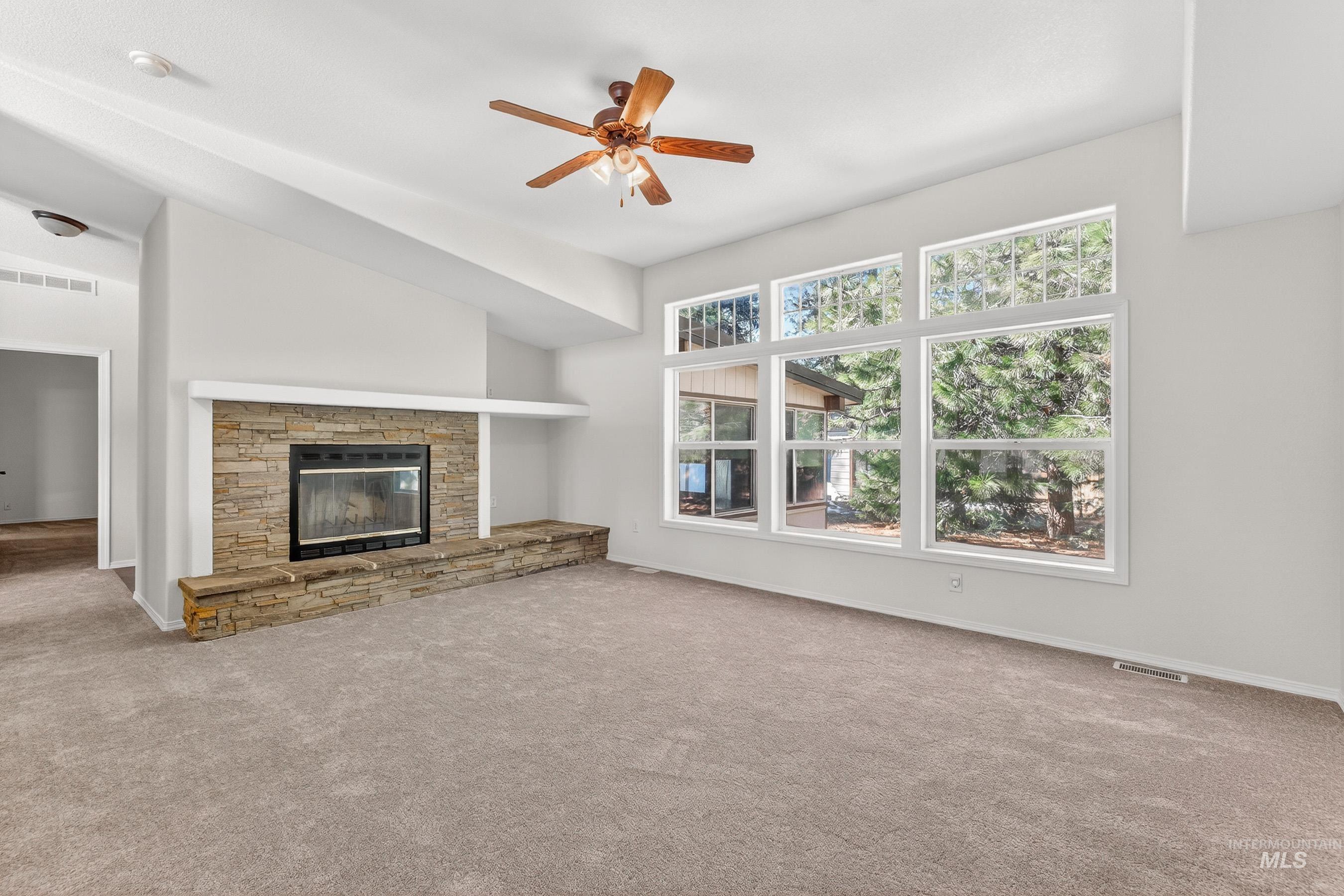 1649 Crown Point Parkway Cascade, ID 83611 - Photo 9 of 24 Spacious living area featuring a stone-clad fireplace with a hearth, large picture windows, vaulted ceilings, and plush carpeting