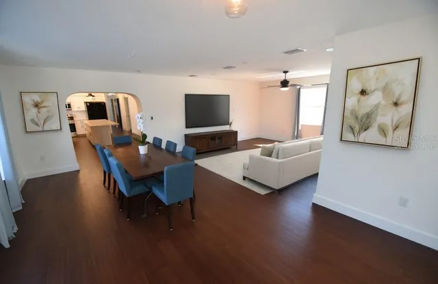 a view of a livingroom with furniture wooden floor fireplace and windows