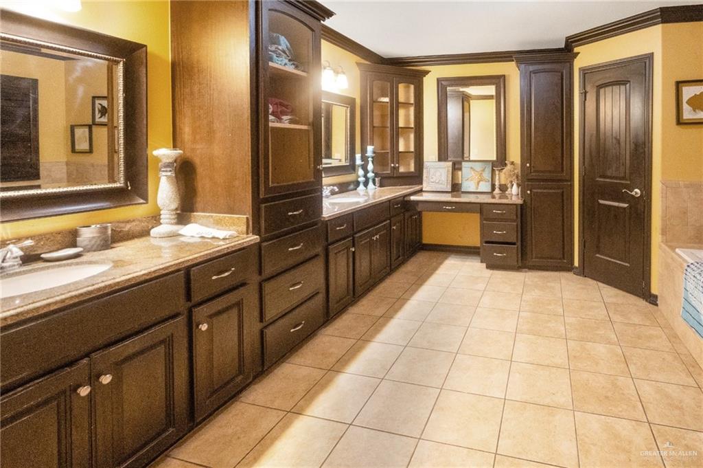 22811 Skinner Road Edcouch, TX 78538 - Photo 22 of 38 Dual vanity with inset sinks, extensive dark wood-finish cabinetry, built-in vanity desk, integrated storage tower, and tiled flooring