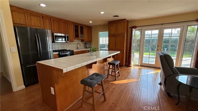 a kitchen with stainless steel appliances a refrigerator a sink dishwasher a stove a refrigerator white cabinets and wooden floor