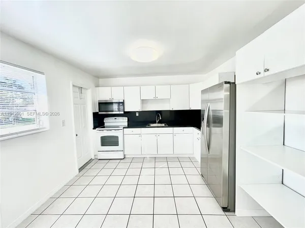 a kitchen with stainless steel appliances a refrigerator and white cabinets