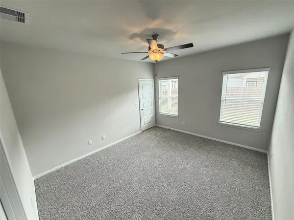 an empty room with windows and fan
