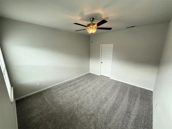 an empty room with a window and a fan