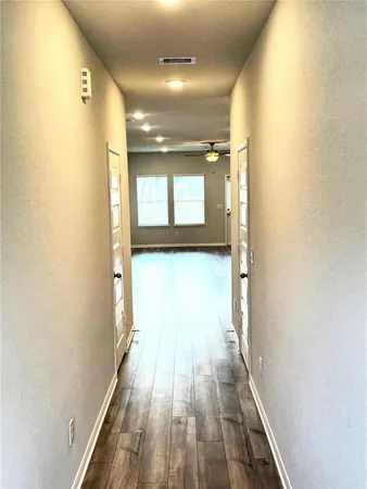 a view of a hallway with wooden floor and a bathroom