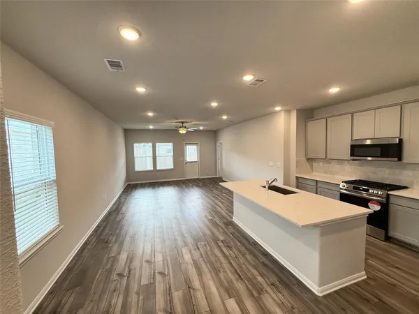 a large kitchen with stainless steel appliances granite countertop a large counter top a stove a sink and a refrigerator