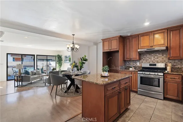 a kitchen with stainless steel appliances granite countertop a stove top oven a sink dishwasher a dining table and chairs with wooden floor