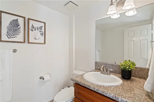 a bathroom with a granite countertop sink a toilet and mirror